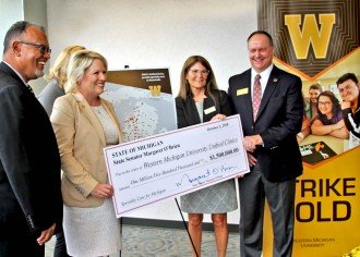 WMU and a state official pose with a ceremonial check for the Unified Clinics.