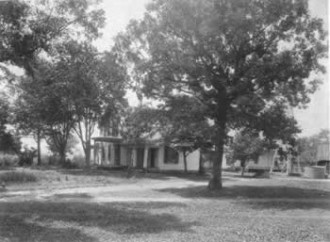 Hindes Cottage stands on a field surrounded by mature trees