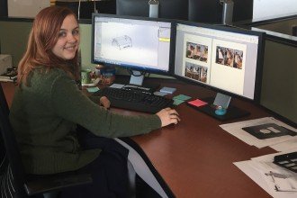 Emily Gruss sitting at a desk in front of two computer displays.