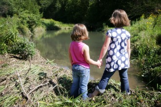 Two little girls on a river bank.