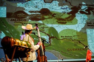 Ensemble member on stage discussing a projection of a map.