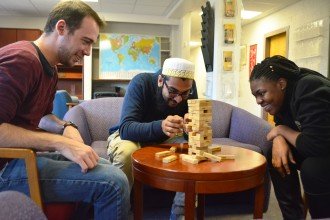 Domestic and international students enjoy a game of Jenga in the common room of their housing.