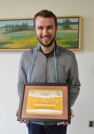Matthew Kornas with framed leadership award.