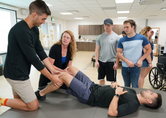 A Doctor of Physical Therapy student completes hands-on learning with a classmate acting as a patient.