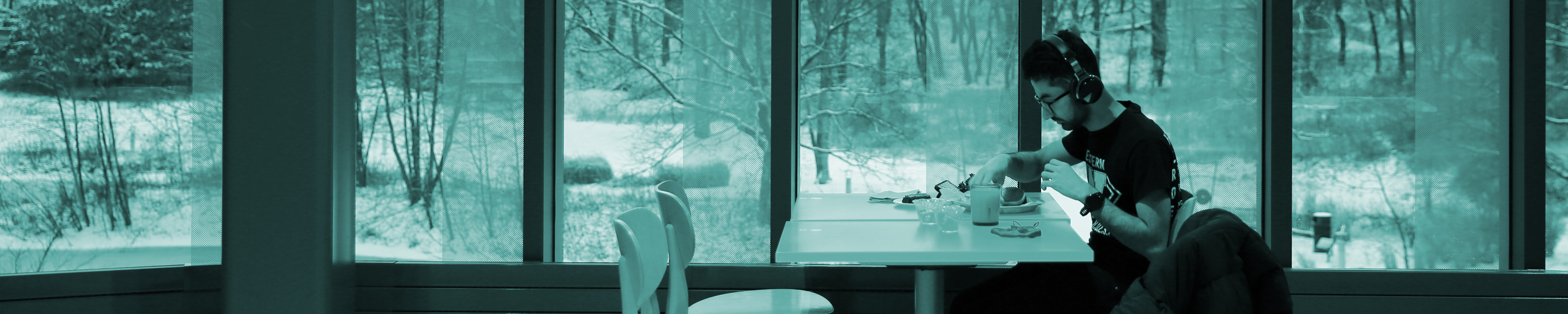 Student sitting by window in Valley Dining Center, snowy background