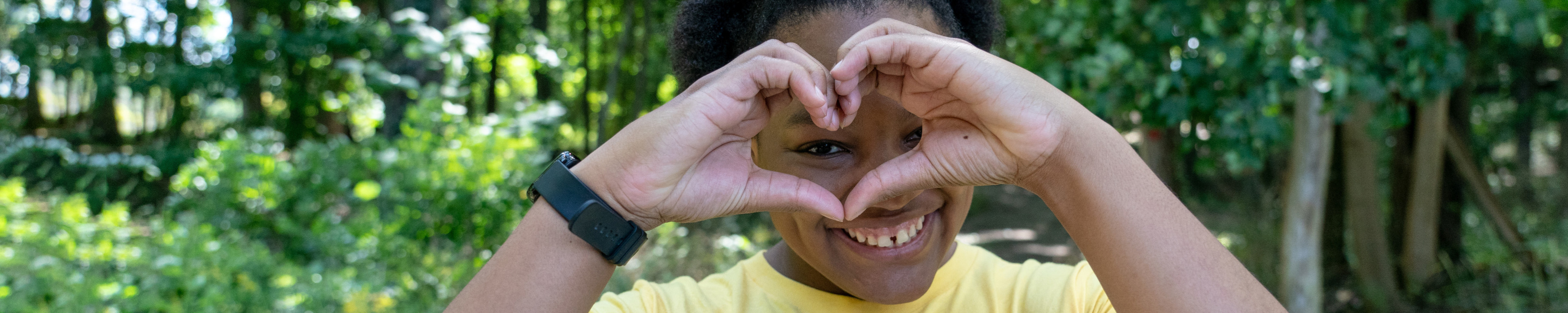 A student forms a heart with her hands in front of her face.