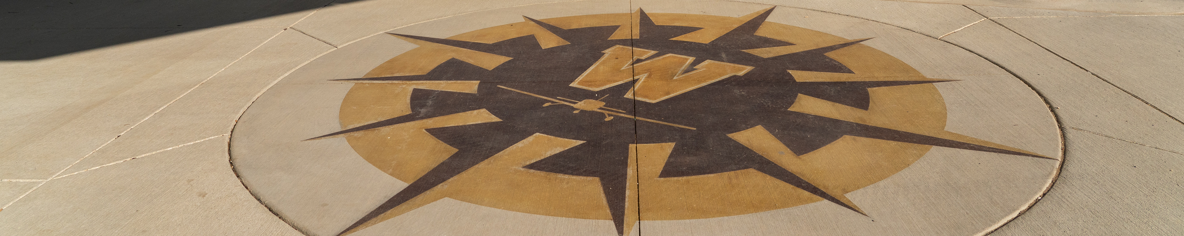 A WMU compass mural on concrete at WMU's Aviation Education Center in Battle Creek
