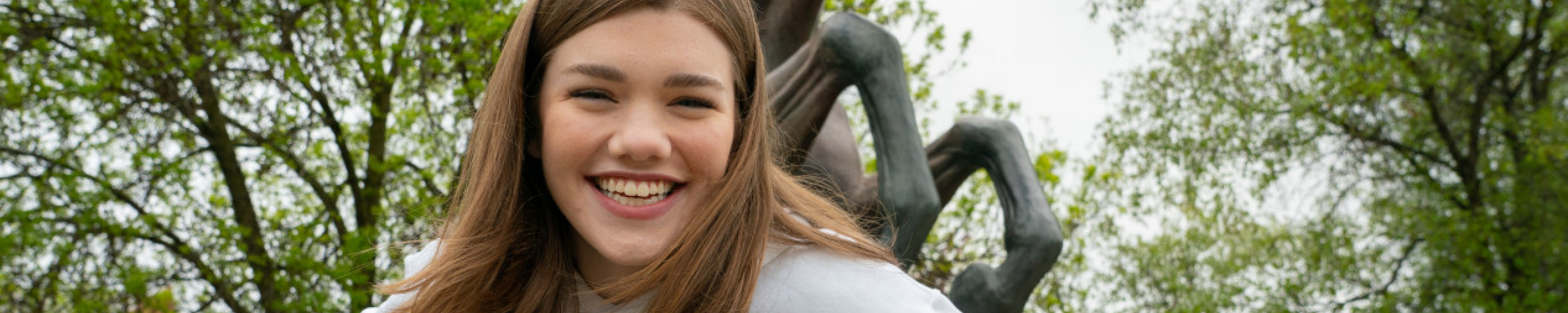 A student smiling in front of the Bronco statue.