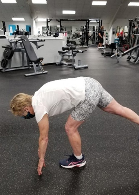 woman bending over to touch the floor while in a gym.