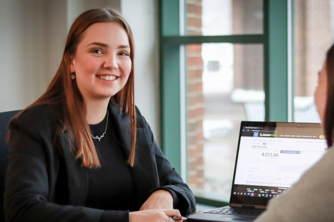 Personal financial planning student smiling in front of a laptop.