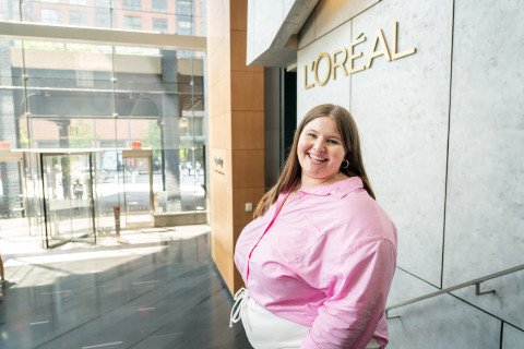 Student standing outside of building with Loreal sign