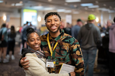 Two students are hugging at an event.