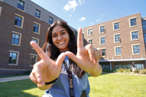 Student outside of Western Heights making the W with her hands.