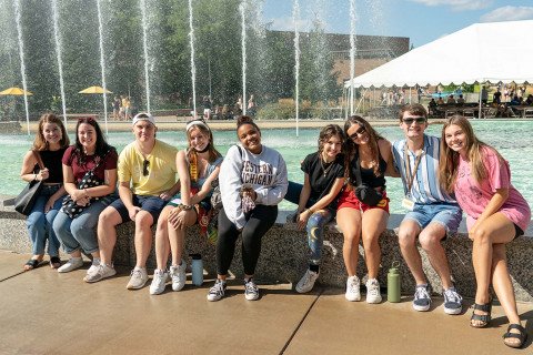 Group of students sitting on the edge of the fountains on main campus.