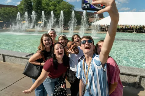 Group of students on main campus, near the fountains taking a selfie photo.