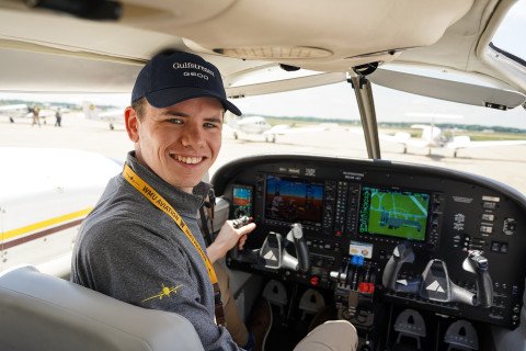 Male student in a cockpit smiling behind him.