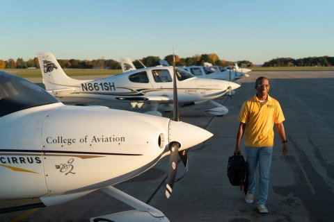 Student walking among several aircrafts at the College of Aviation.