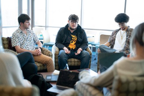 Male students around a table having a discussion.