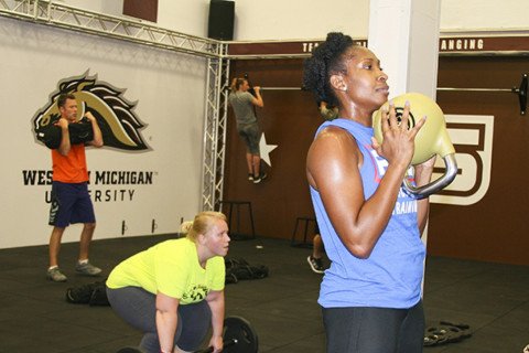People working out in F45 class. Black female with medicine ball and other people in the back working out