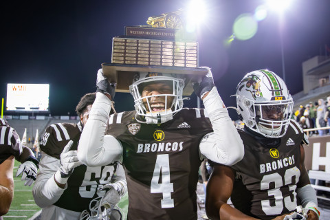 A football player holds a trophy over his head.