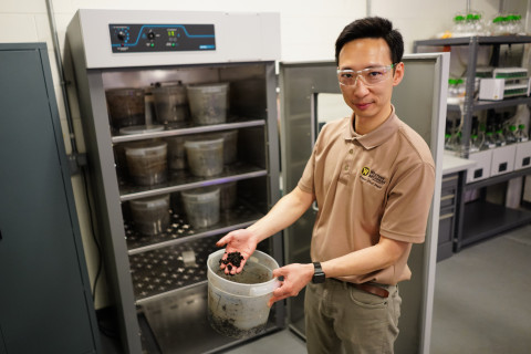 Jason Wang holds a bucket with composted material.
