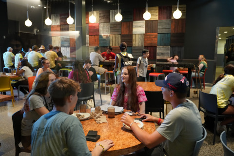 Students sitting at a table in the VDC near; dining room is full