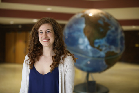 Student standing in front of a globe