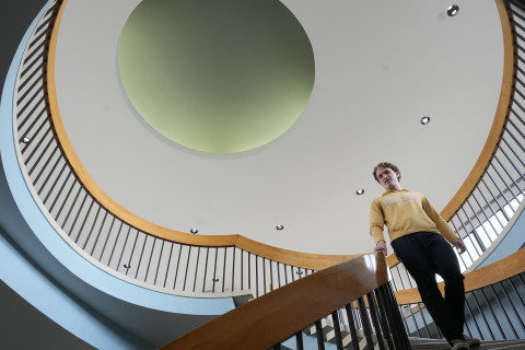 A student descending the staircase in Faunce Student Services Building.