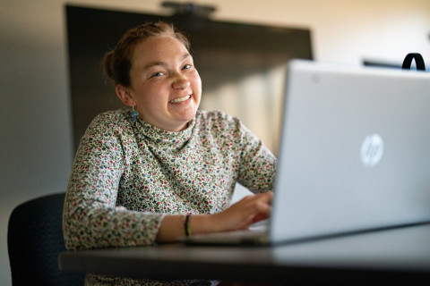 Girl on her computer, smiling at the camera.