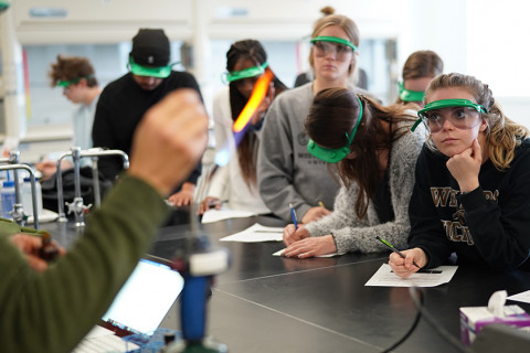 Students in lab observing professor using fire torch