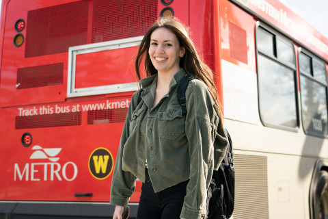 A student standing in front of a Metro bus.