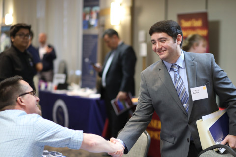 Student in suit shaking professional's hand