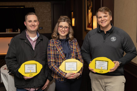 Three students holding lemon-shaped awards.