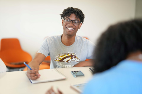 student smiling writing in notebook