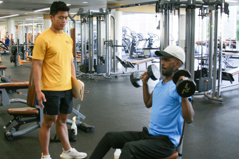 Personal Trainer working with a client who is doing a dumbbell exercise