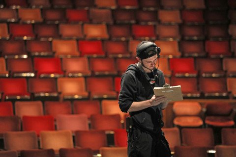 young man standing in theatre with a clipboard