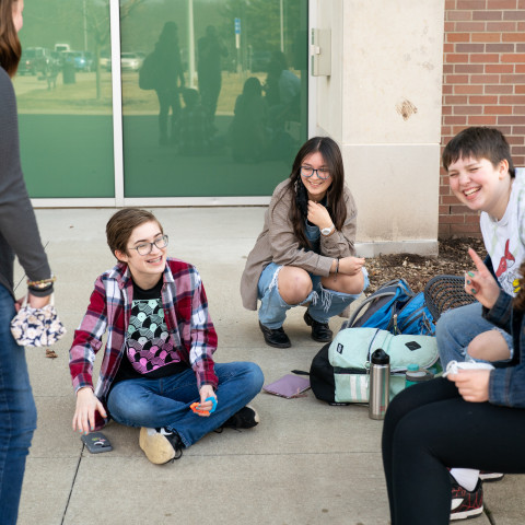 Students sit on the sidewalk talking.