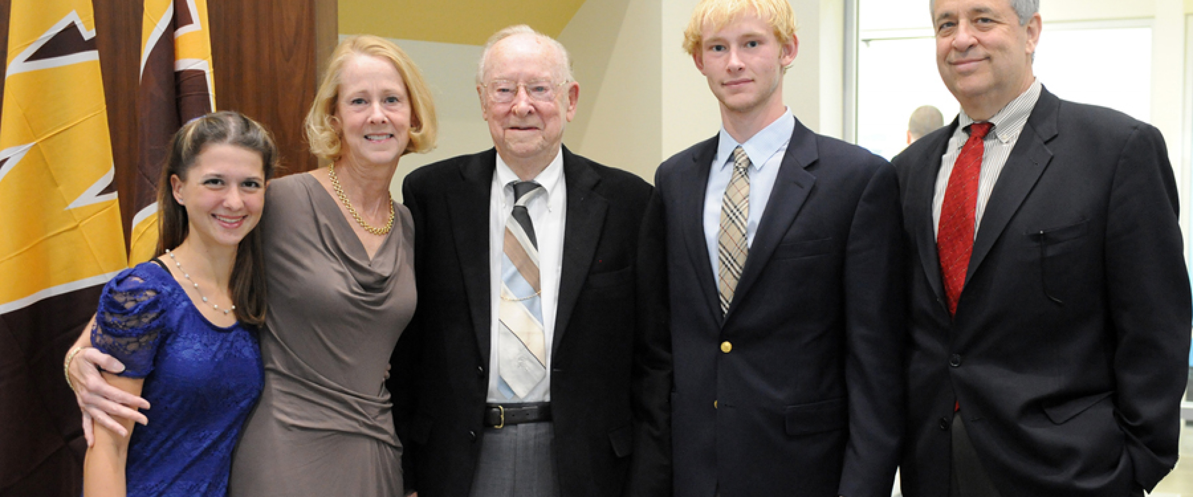 Carl Lee with his daughter, son in law, and grandchildren standing in the lounge at the reopening of the honors college.