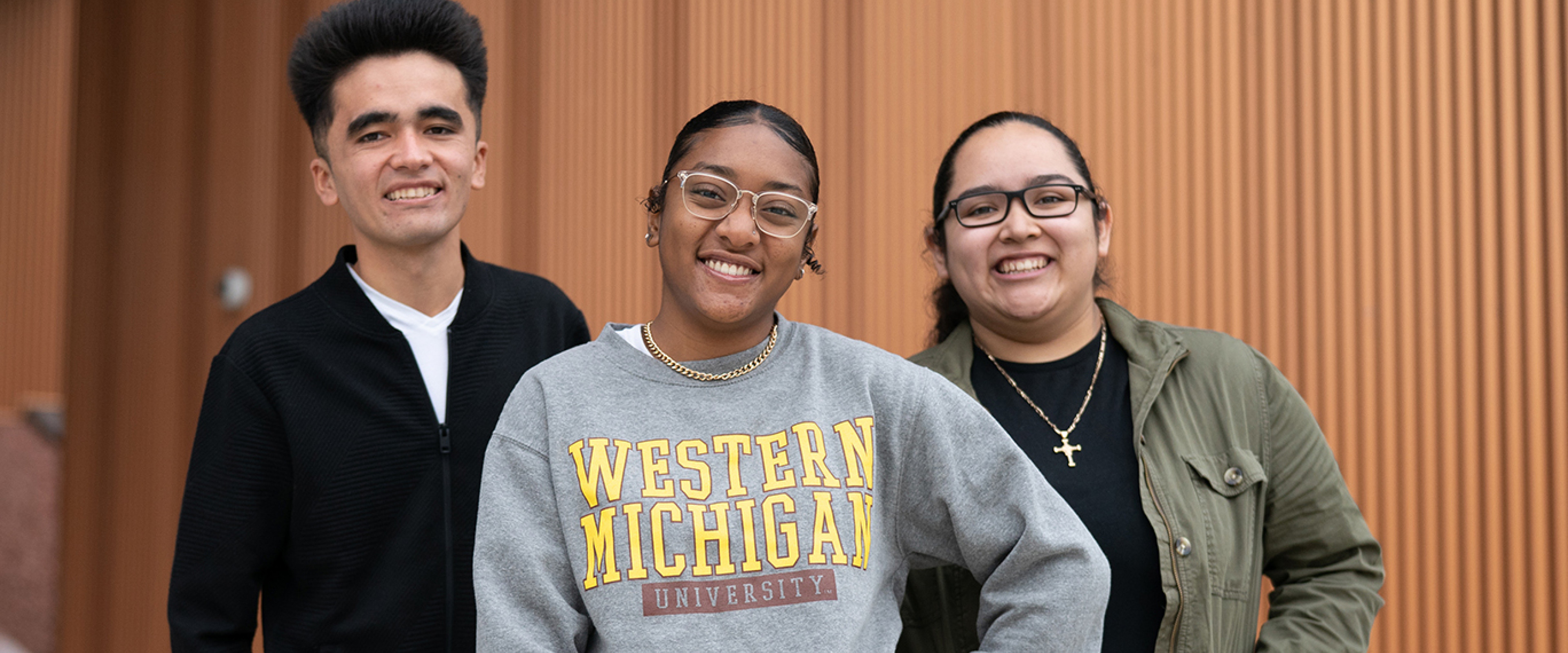 Three WMU students standing in front of a wooden wall. 