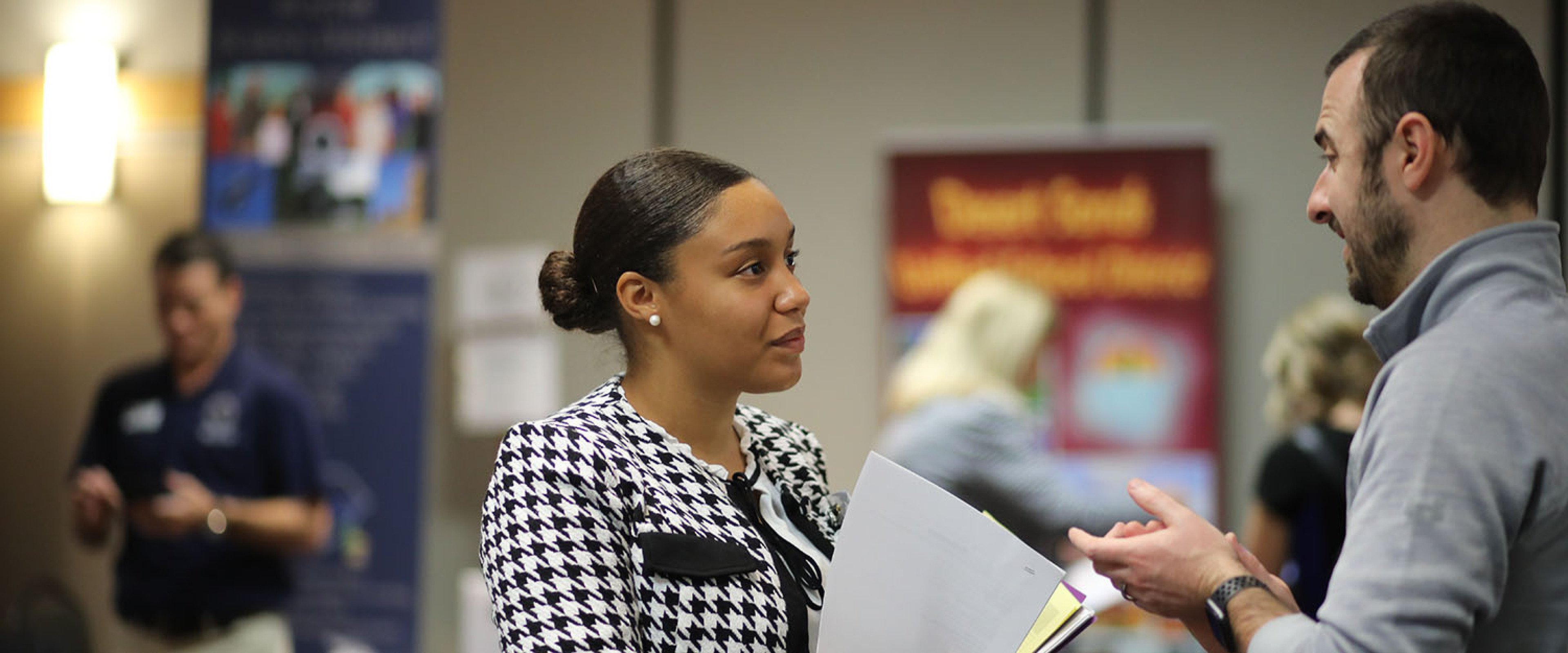 WMU student in professional attire networking with another person.