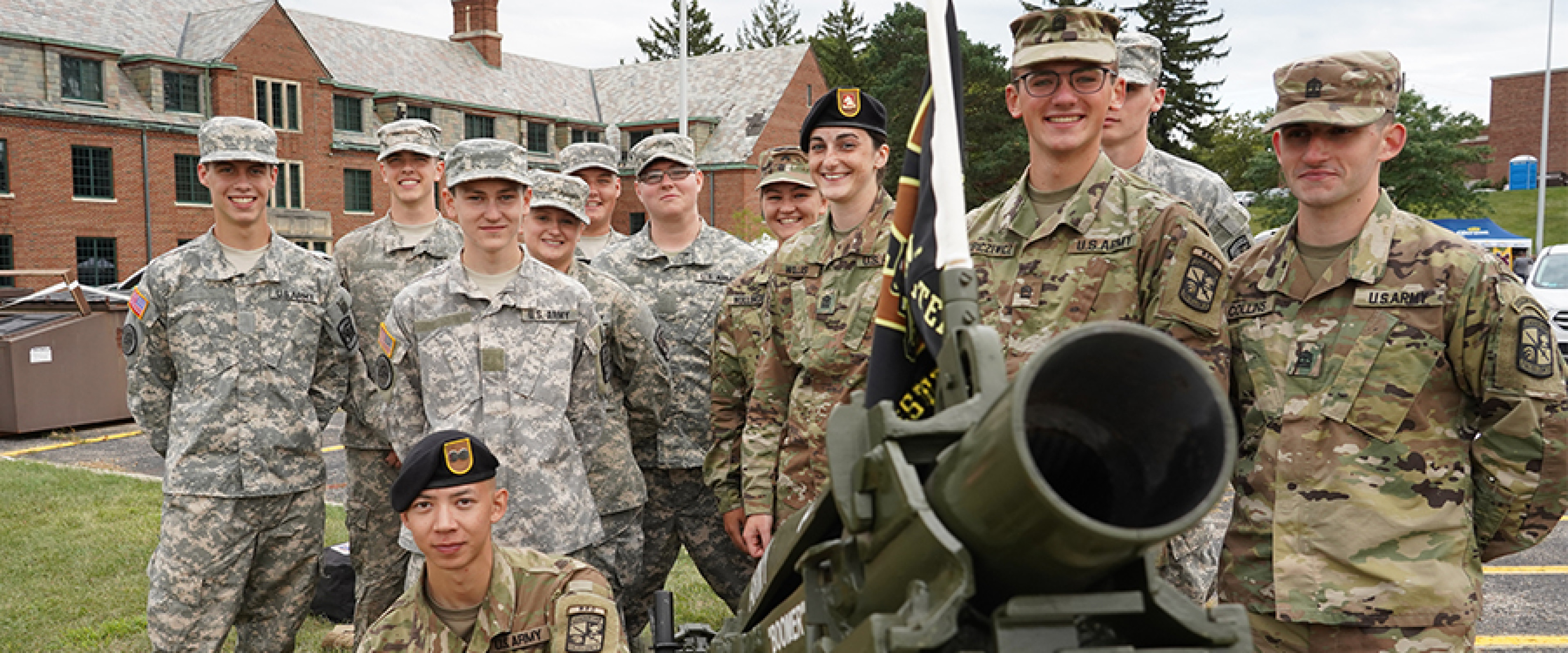 Group of cadets in uniform with Boomer the canon.