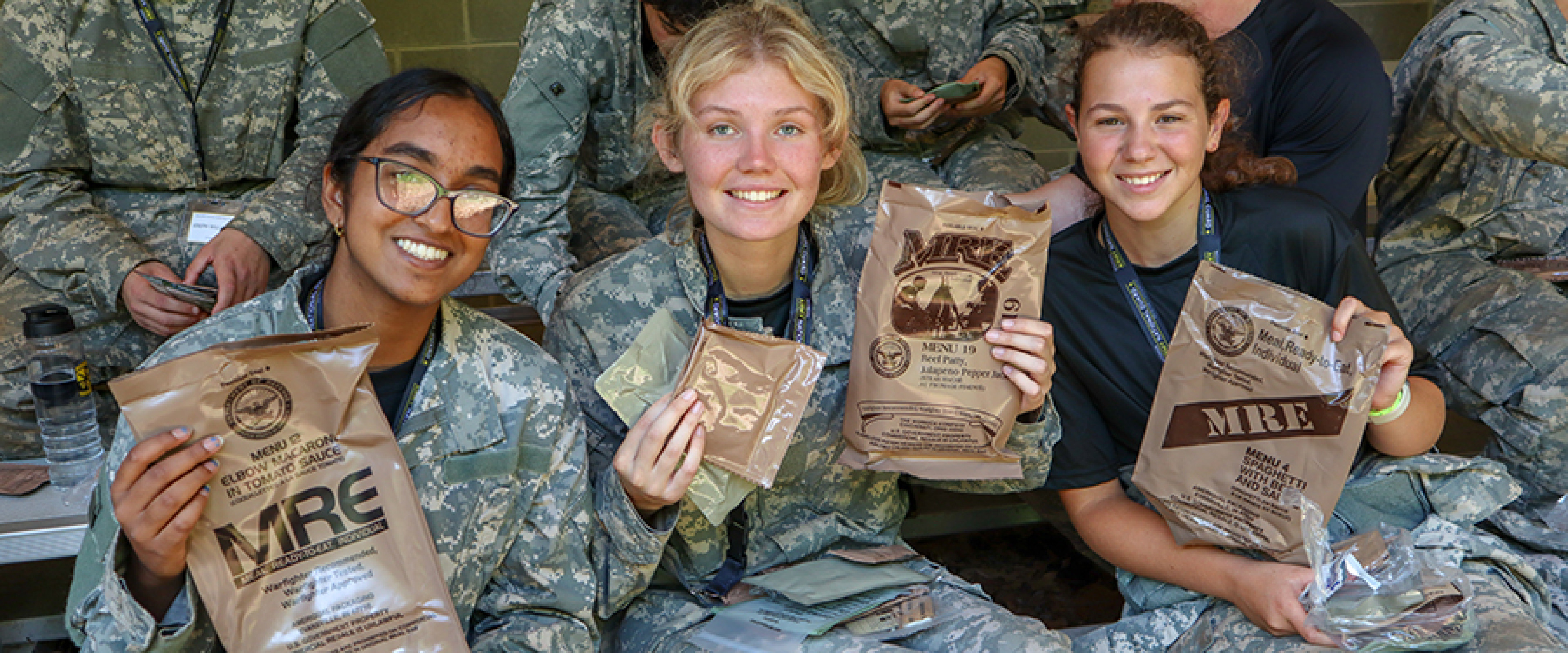 Students holding up Army-issued meals while at a summer camp.