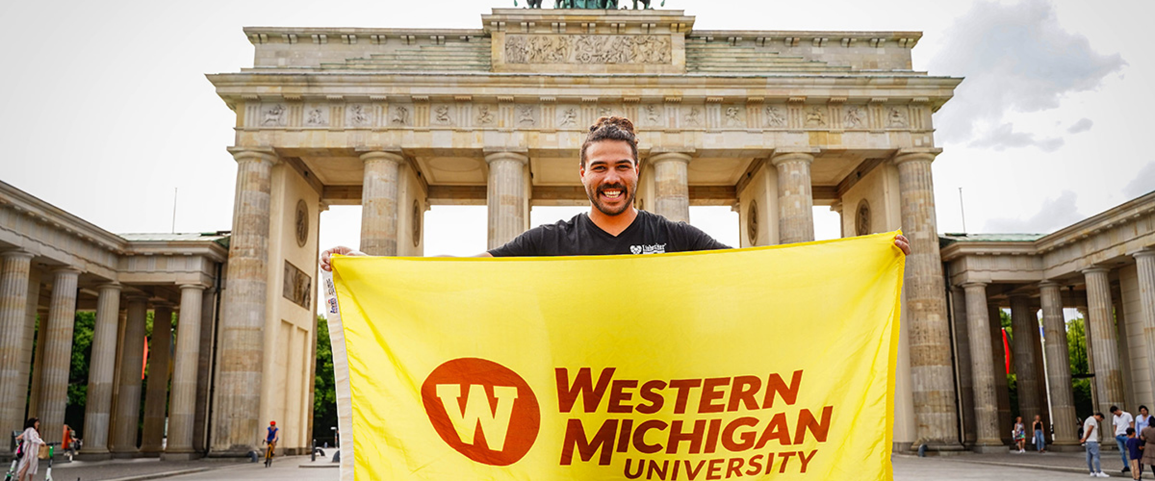 A student, on a study abroad in Germany, holds the Western Michigan University flag. 