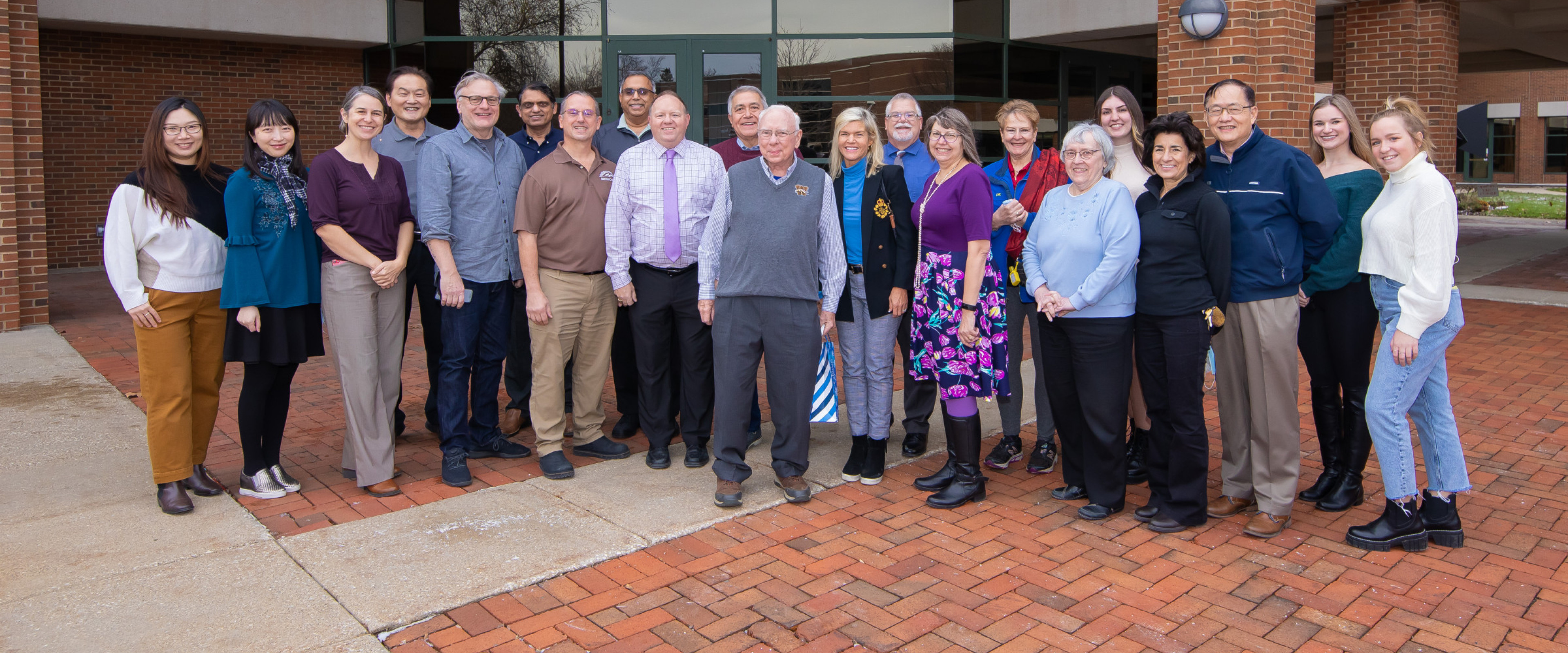 Dr. Tom Carey, surrounded by faculty and friends outside of the Haworth College of Business.