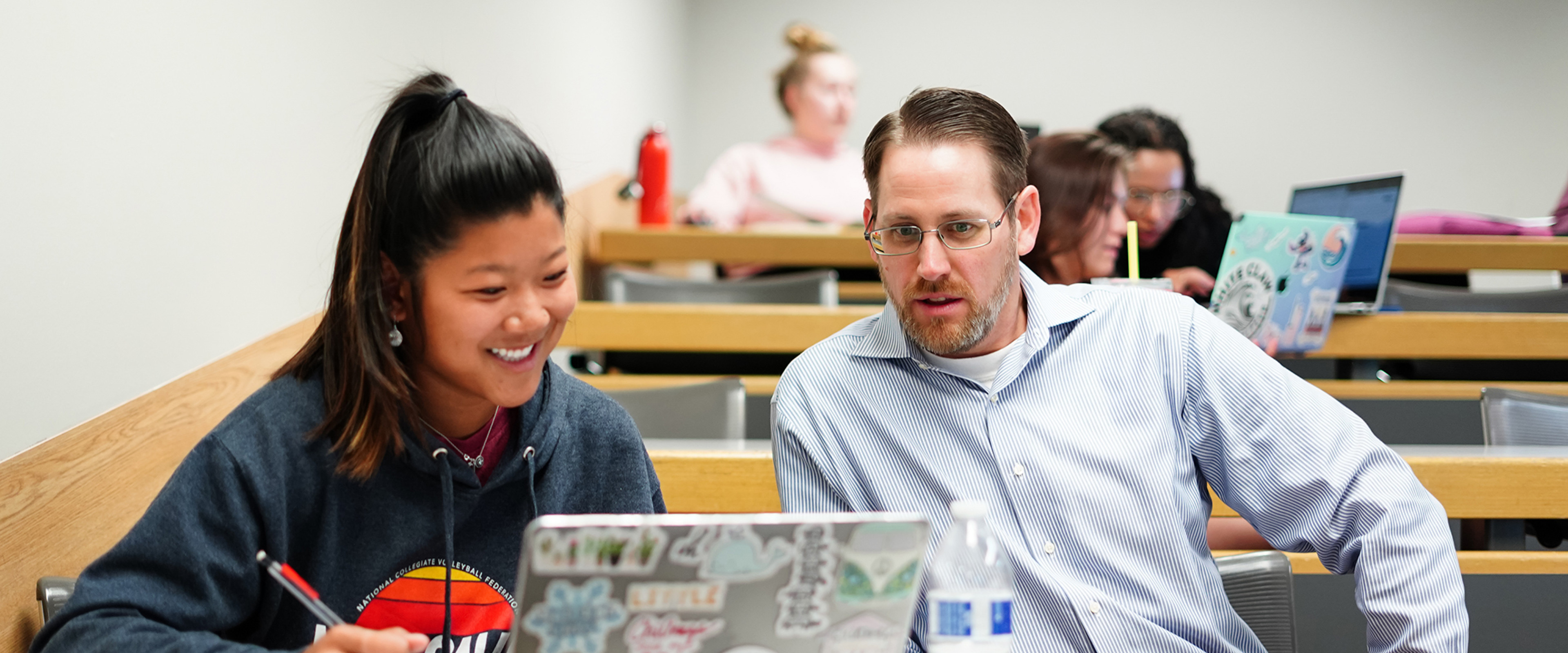 A student and Dr. Matt Ross are chatting while looking at a laptop.