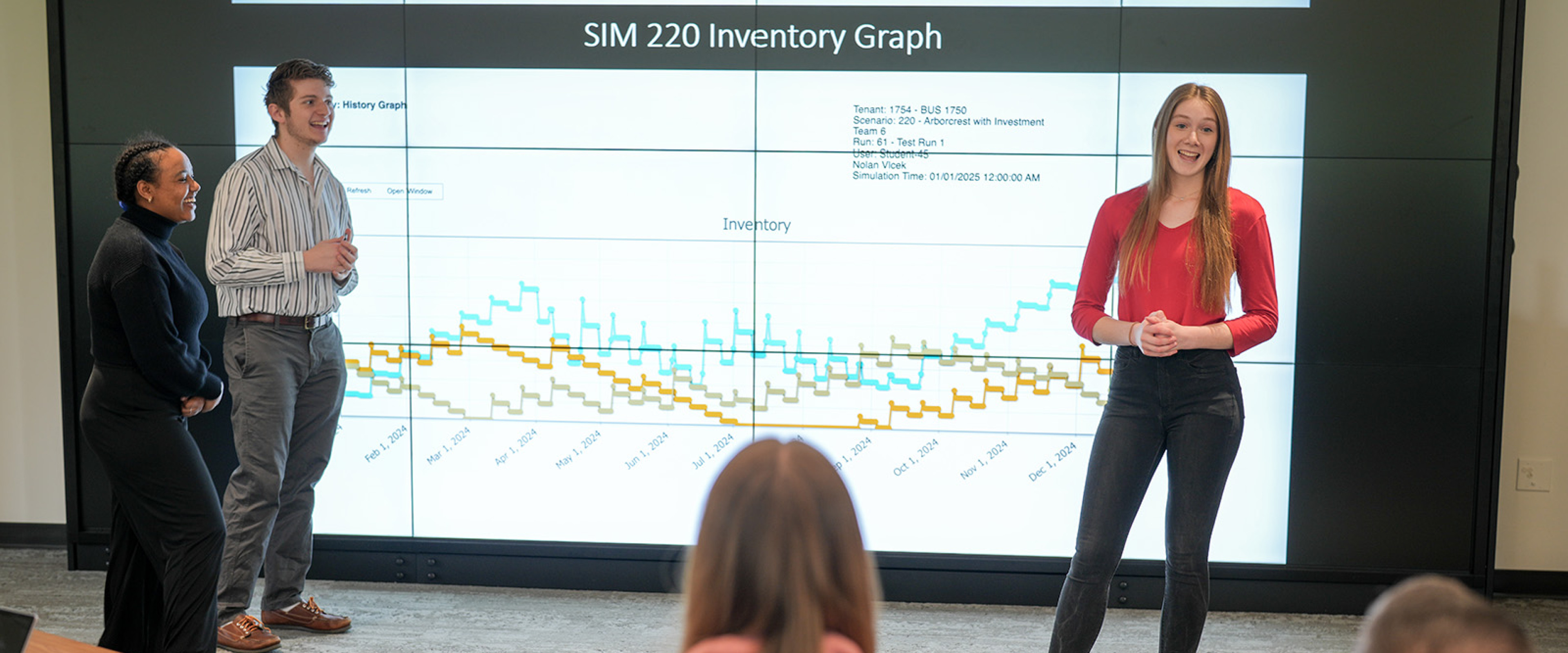 Three students are presenting an inventory graph in the Dean's Conference Room.