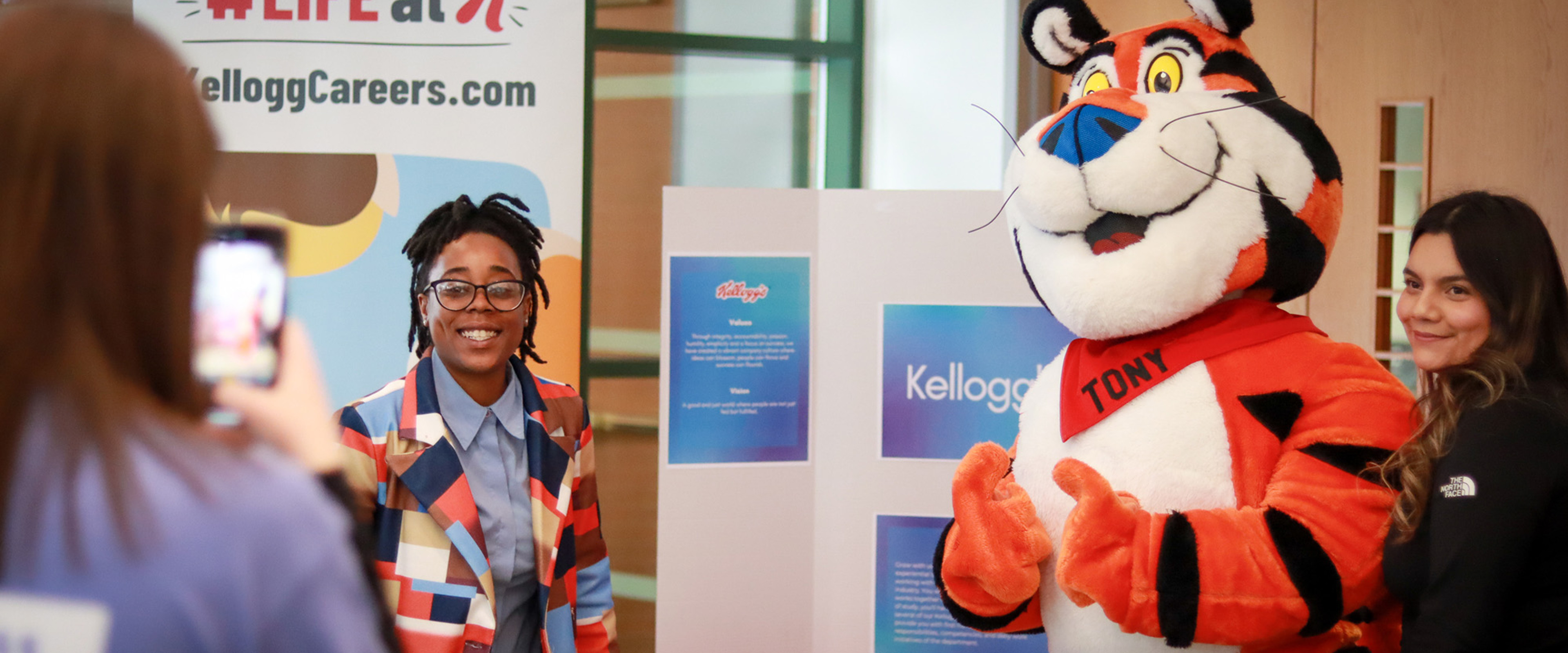 A student is getting a photo with Tony the Tiger at a Business Externship Program event.