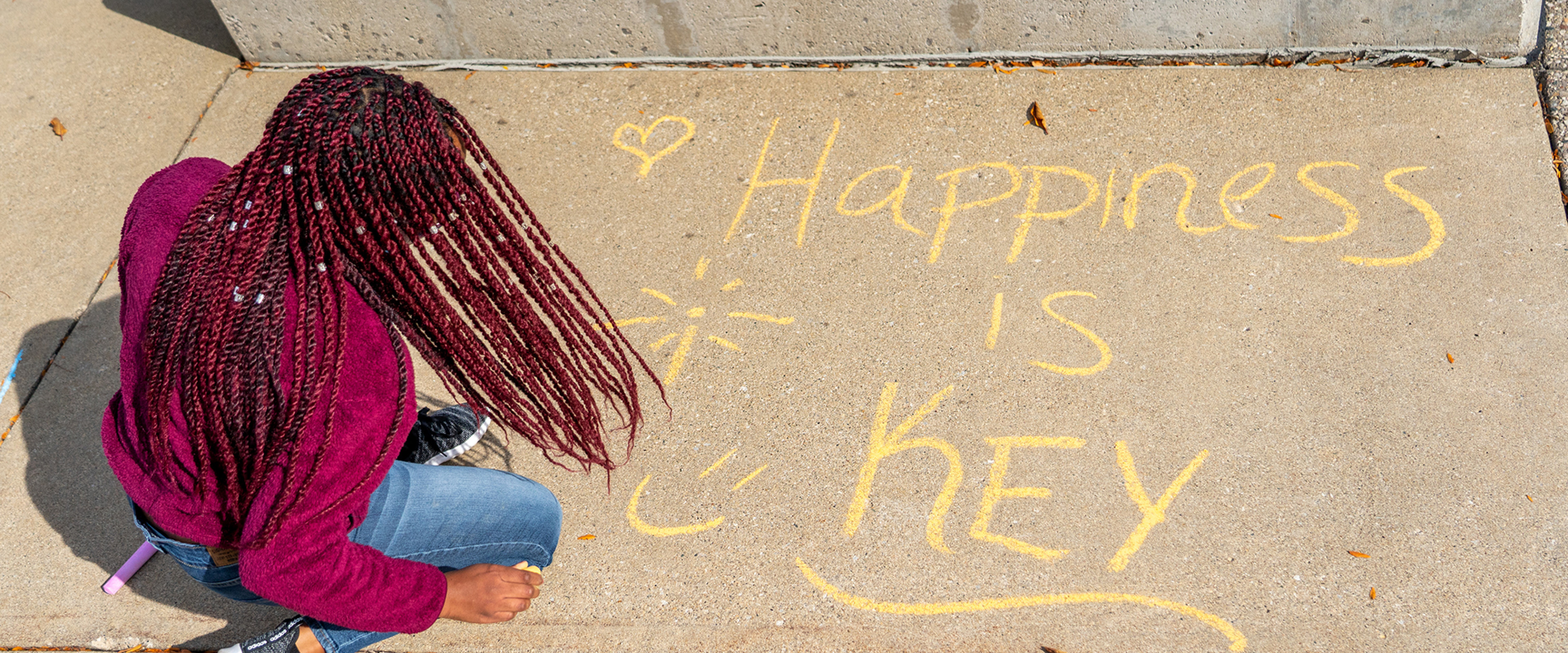 Girl writing on the sidewalk "Happiness is key"