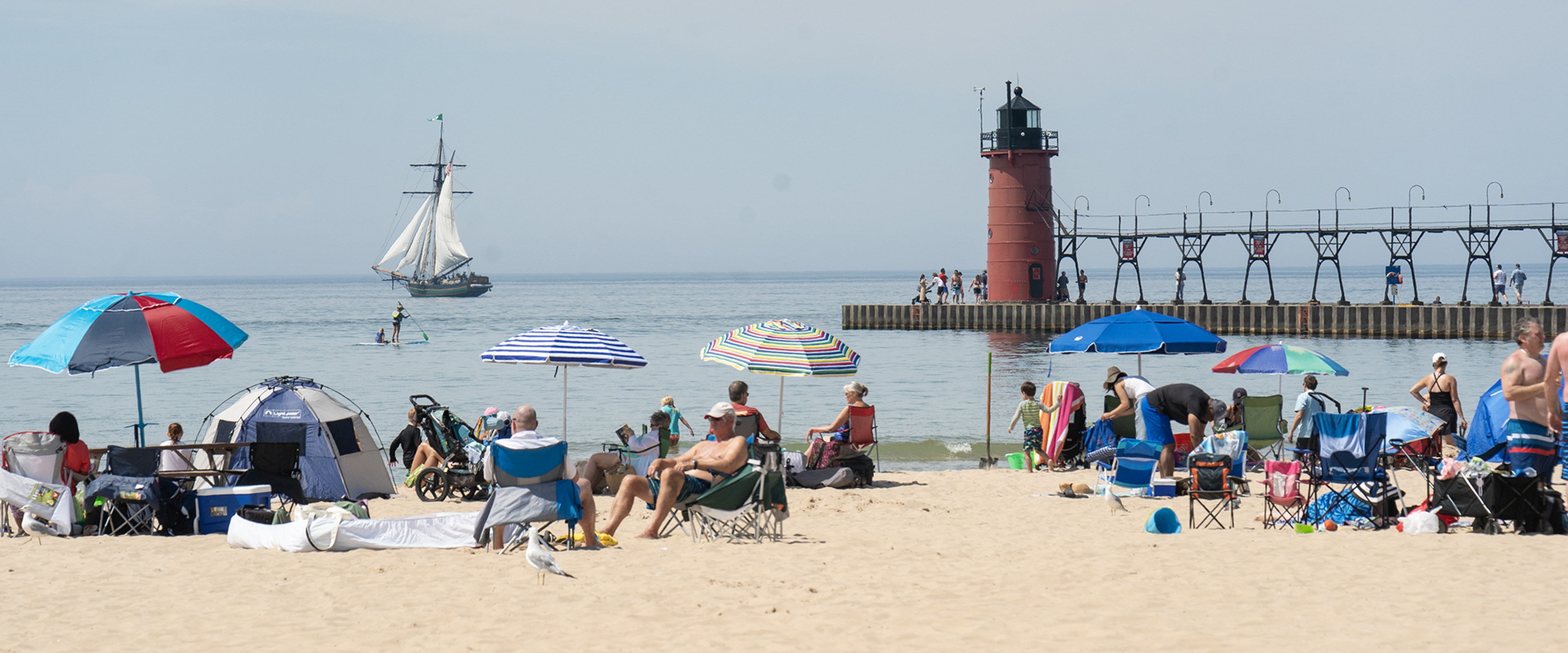 Popular Lake Michigan beach, South Haven, pier and lighthouse visable beyond the crowded beach.