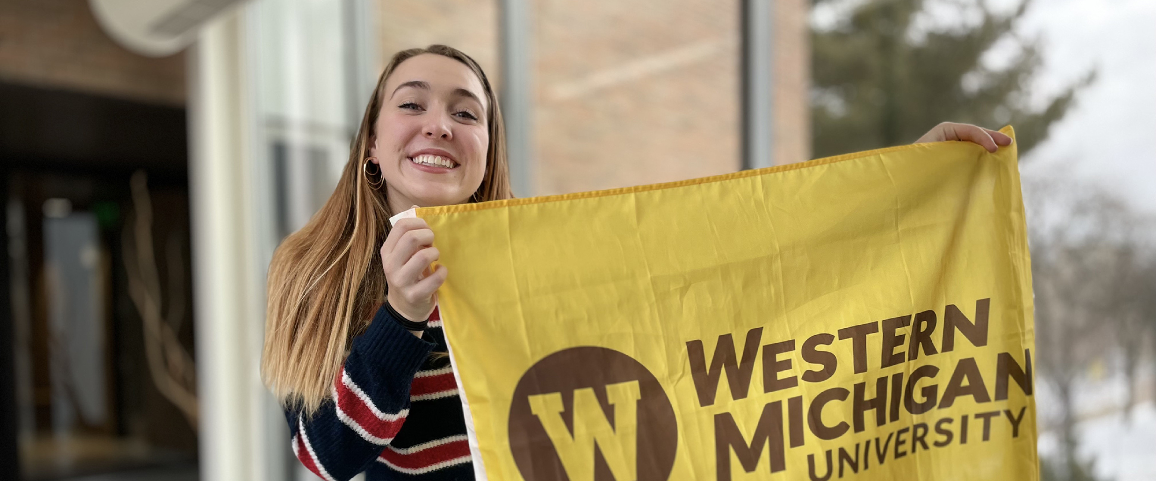Nadya Beyar holding a Western gold and brown flag on main campus.